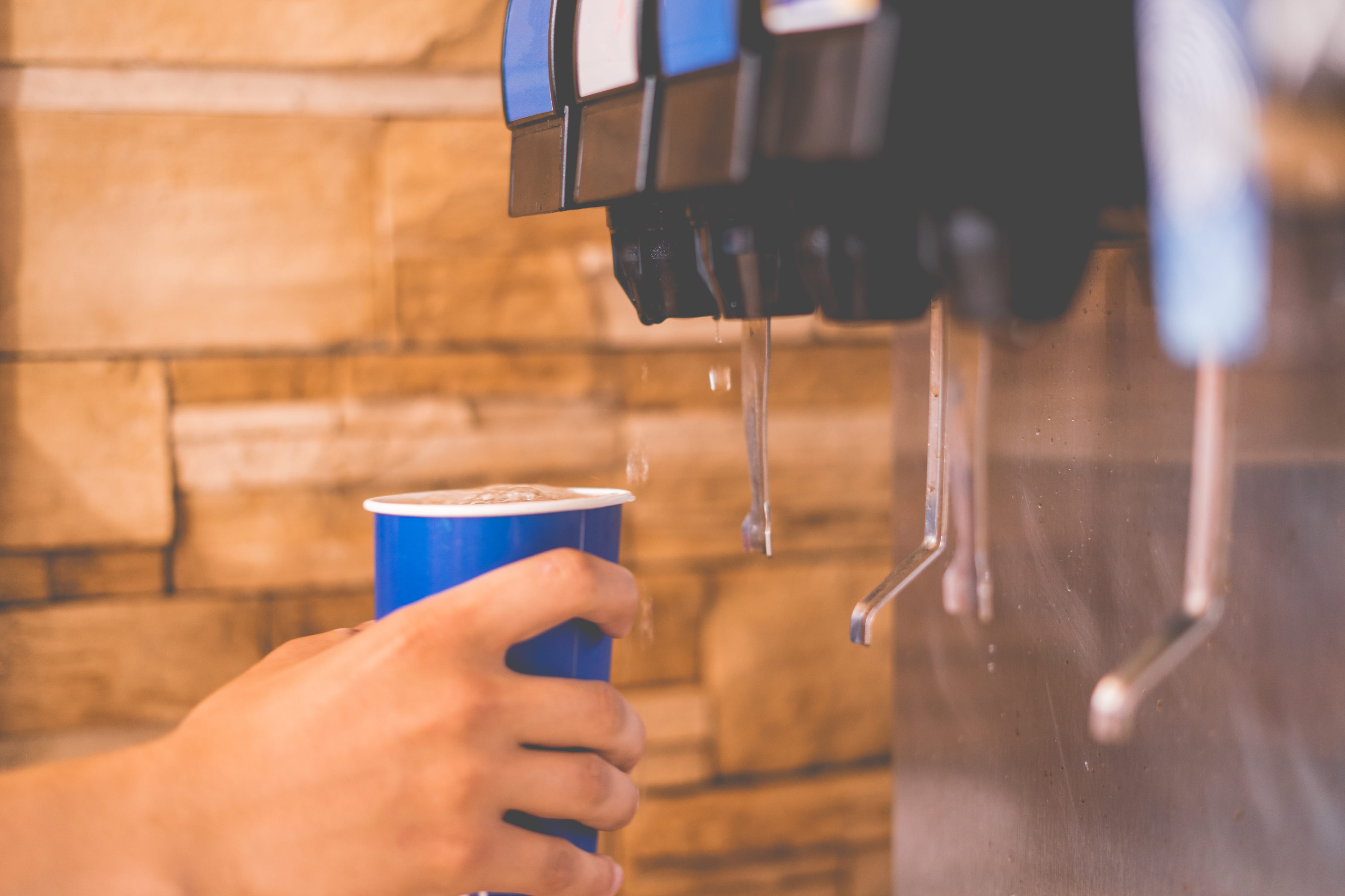 Hand holding a cup using a soft drink vending machine