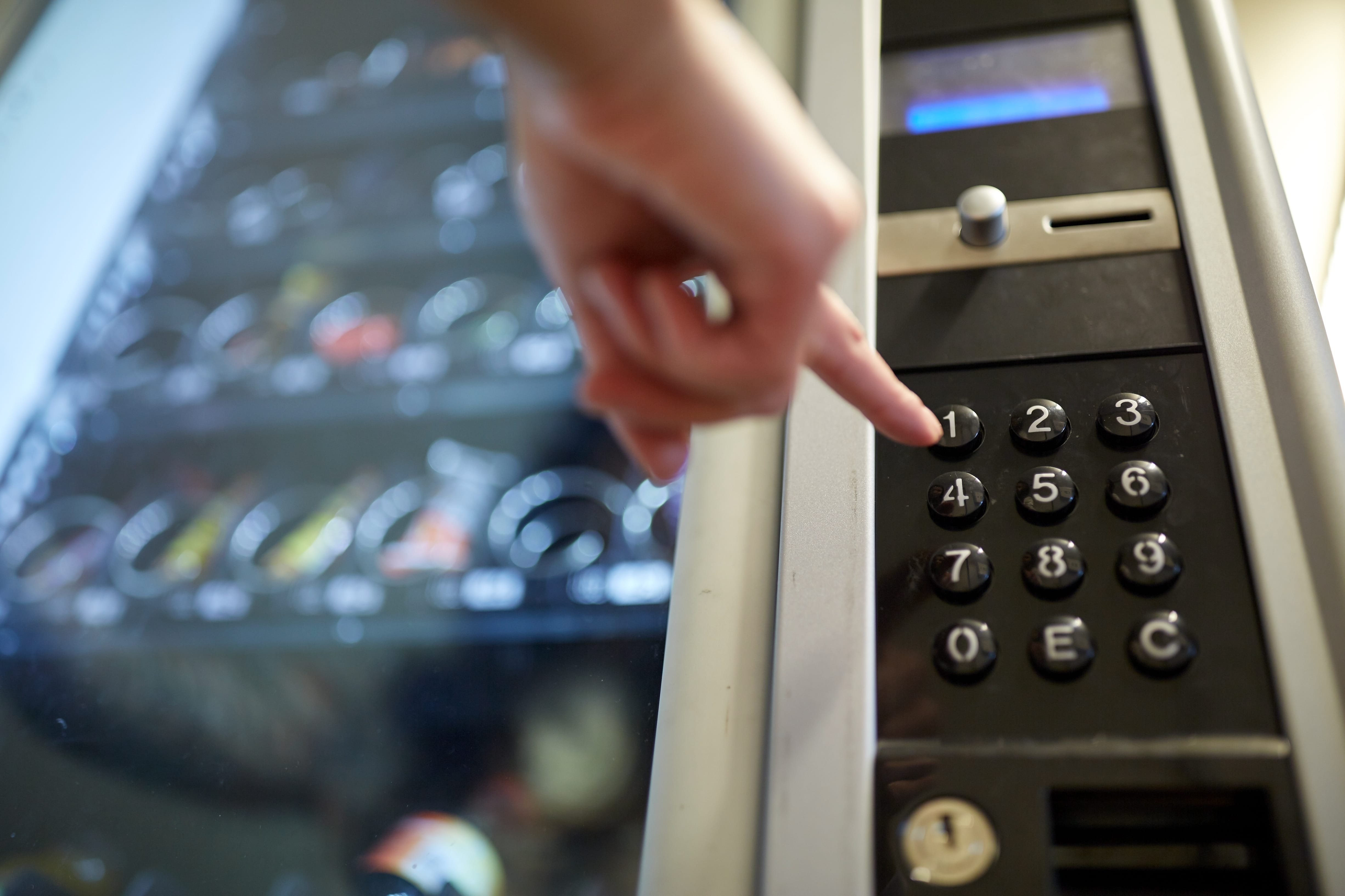 Hand pushing a button on a vending machine